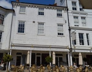 The white weatherboarded frontage of the Tunbridge Wells Hotel on the Pantiles, with outdoor tables under the colonnade